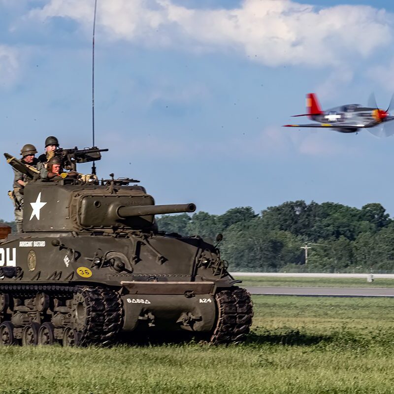 Historic tank with soldiers and vintage aircraft